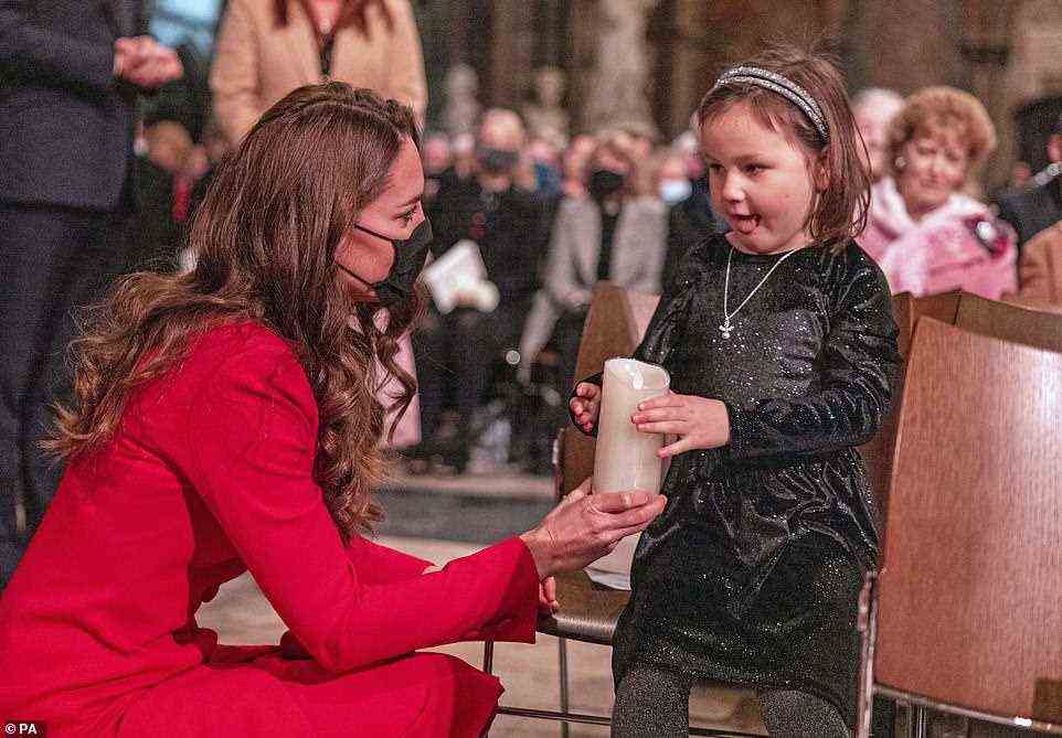 Showing off her maternal side! Kate could be seen sharing a candle with Mila Sneddon, 6, ahead of the Together At Christmas community carol service