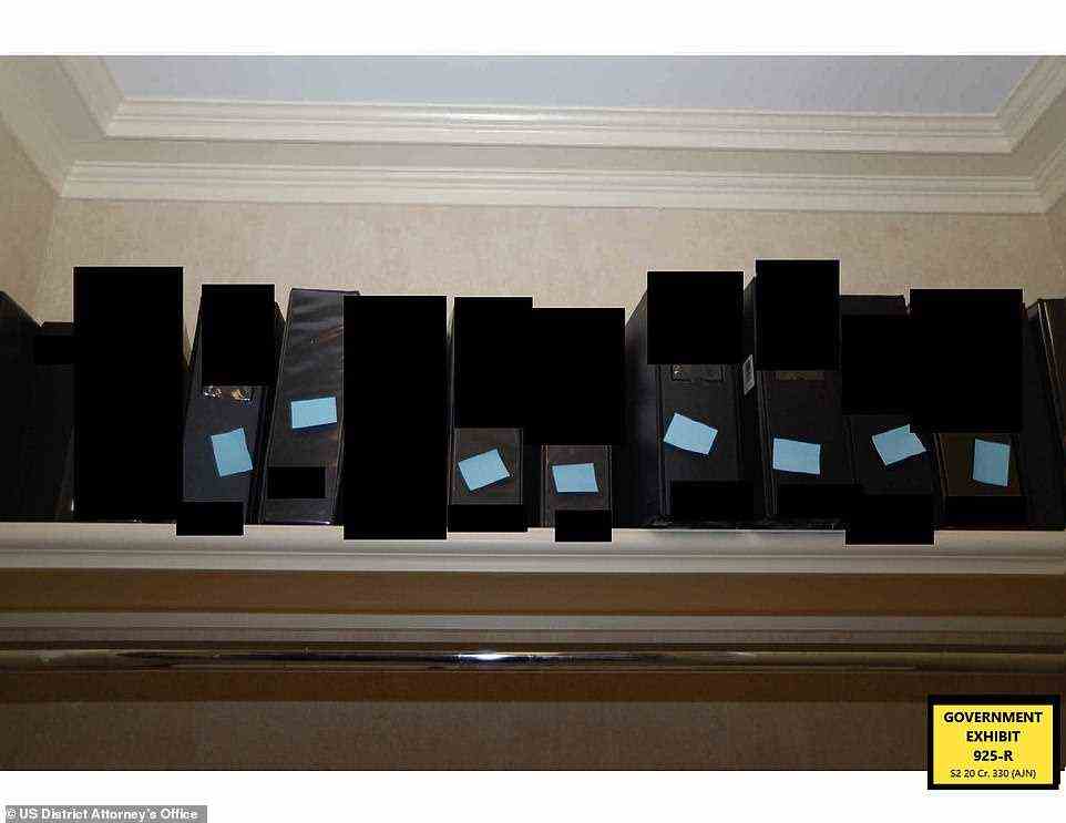 Several labeled binders are seen on a shelf and have been blacked out by authorities