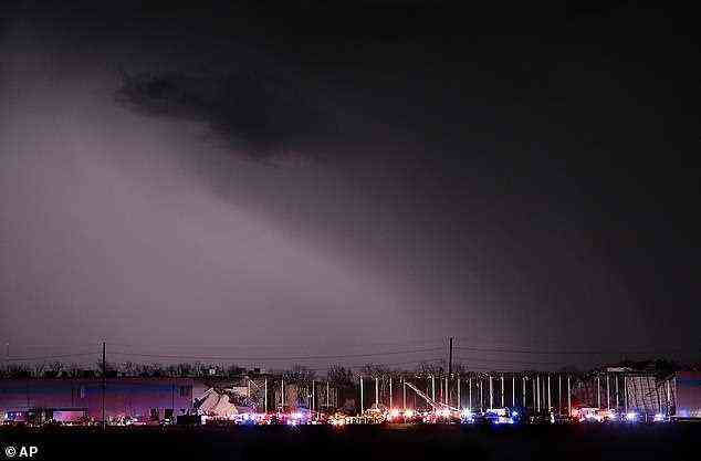 Der riesige Tornado ist als schwarzer Schatten am Himmel zu sehen, während Rettungskräfte auf das Lagerhaus in Edwardsville reagieren