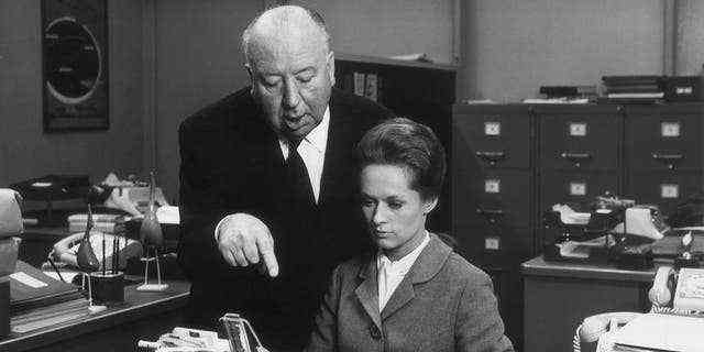 Der britische Regisseur Alfred Hitchcock inszeniert die amerikanische Schauspielerin Tippi Hedren, während sie am Set seines Films vor einer Schreibmaschine sitzt "Marnie."