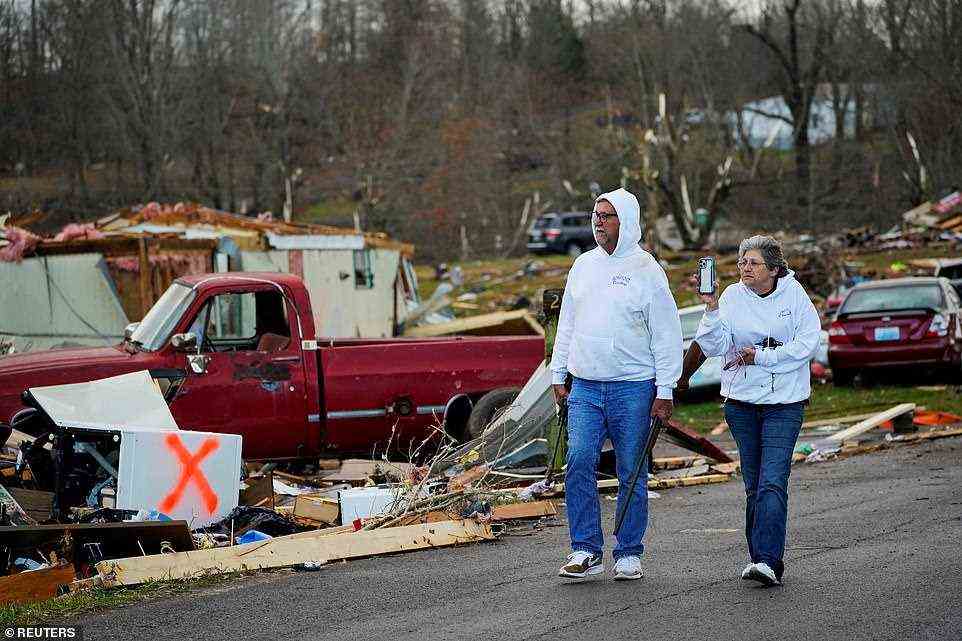Bill Mosley walks with his wife Bonnie surveying the damage while carrying two of his guns, the only items he was able to recover after their home in Earlington, Kentucky was destroyed