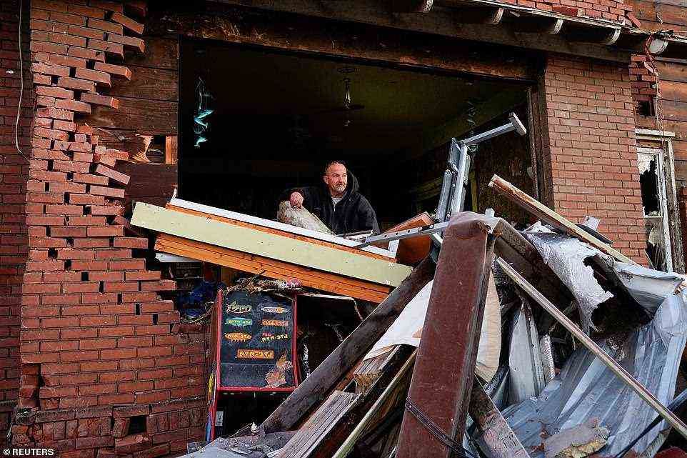 McDill, who continues to spend the night inside his home to protect it from looters, stands in his living room while looking out over the damage and debris on Sunday morning