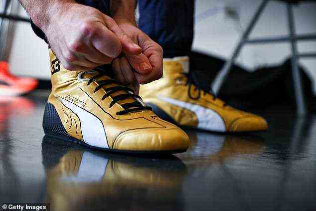 Verstappen bindet die Schnürsenkel seiner speziell angefertigten Sneaker der Sportbekleidungsmarke Puma