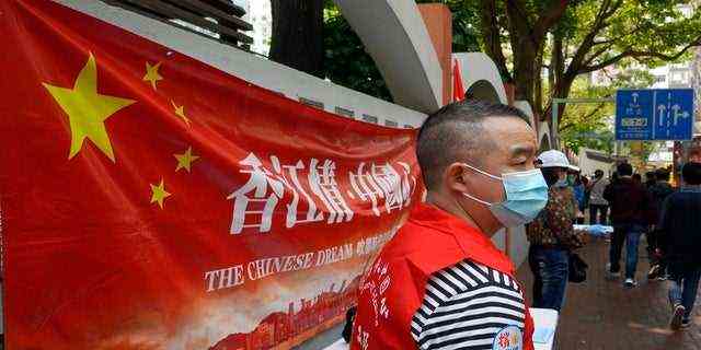 Ein pro-chinesischer Mitarbeiter steht an einem Stand, um einen Vorschlag zur Ausarbeitung von Änderungen der Wahlregeln für Hongkong in einer Straße in der Innenstadt von Hongkong zu unterstützen.  (AP)