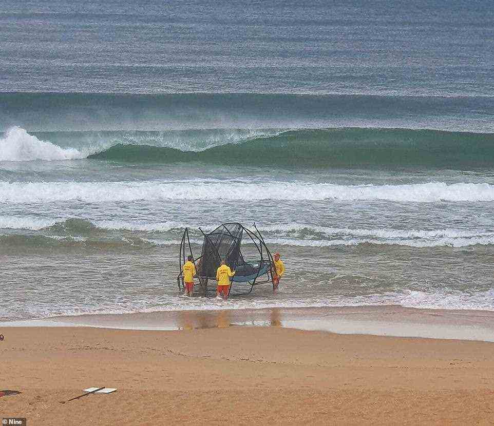 Lebensretter schwammen durch tosende Wellen, um ein Trampolin zu holen, das von einem nahe gelegenen Hinterhof bis zum Wasser geblasen wurde