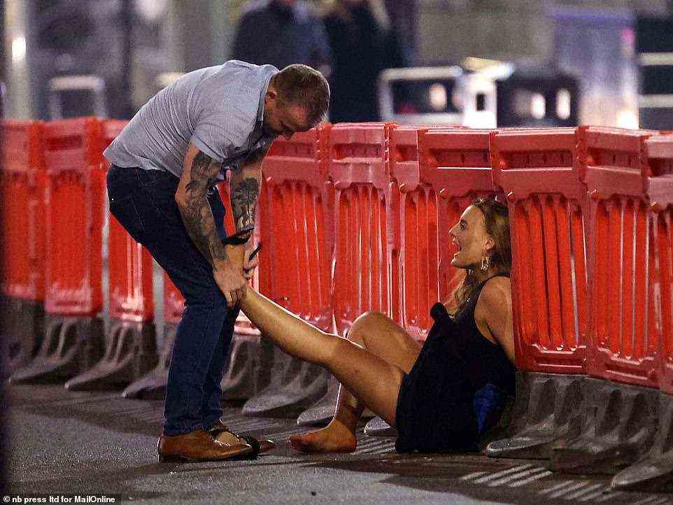 Helping hand: A man assists a fellow reveller with her footwear during an evening out in Leeds last night