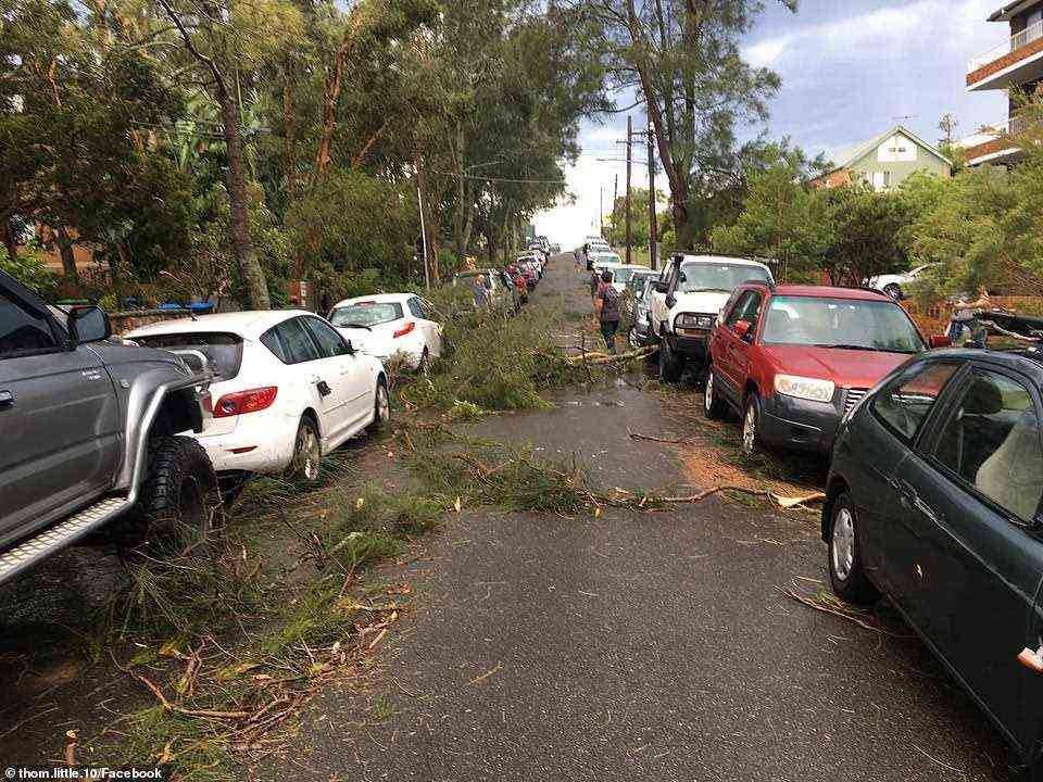 Locals begin cleaning up their streets on Sunday evening after the freak storm lashed the area