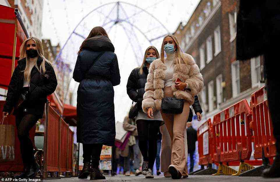 People walk along a shopping street off Oxford Street in London at about 12.30pm today, just four days before Christmas