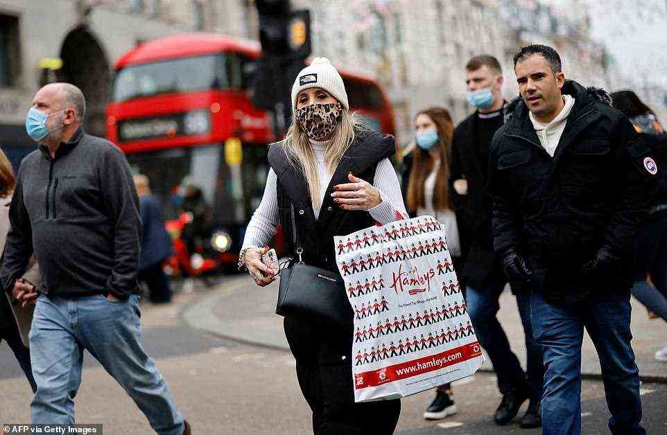 A woman carries a Hamleys Christmas carrier bag as she crosses a road on Oxford Street in London at about 11.30am today