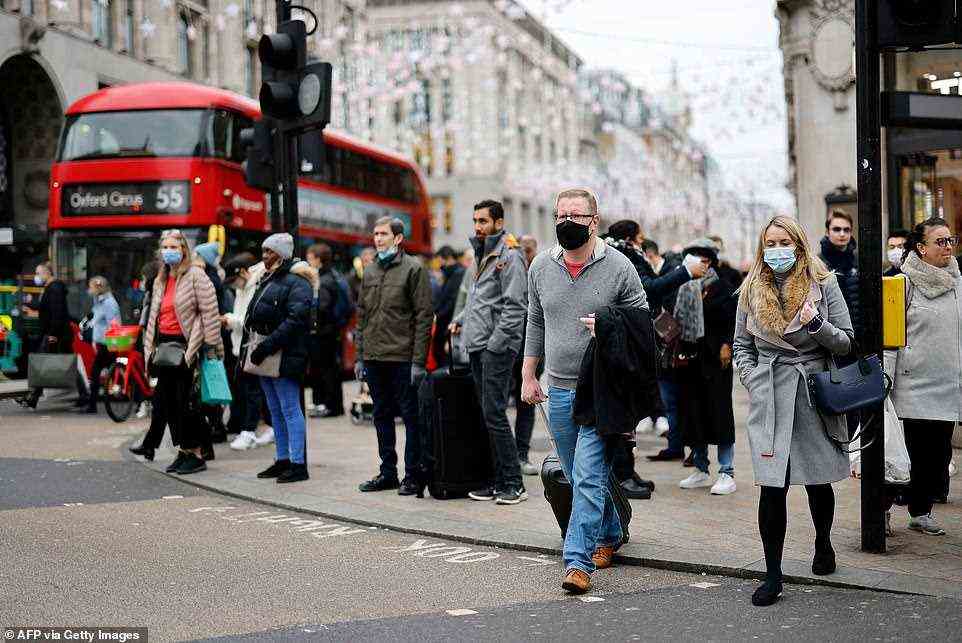 People cross a road on Oxford Street in London at about 11.30am this morning as they do some last-minute shopping