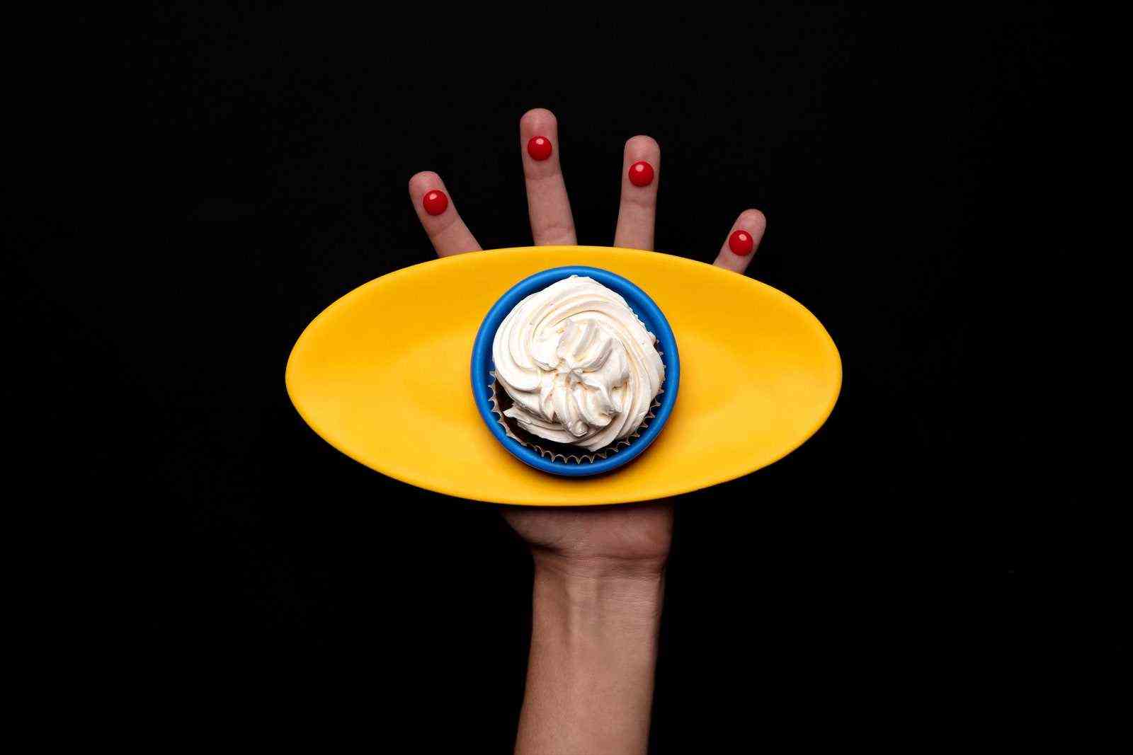 Eine Hand hält eine ovale Platte mit einem Dessert darauf.
