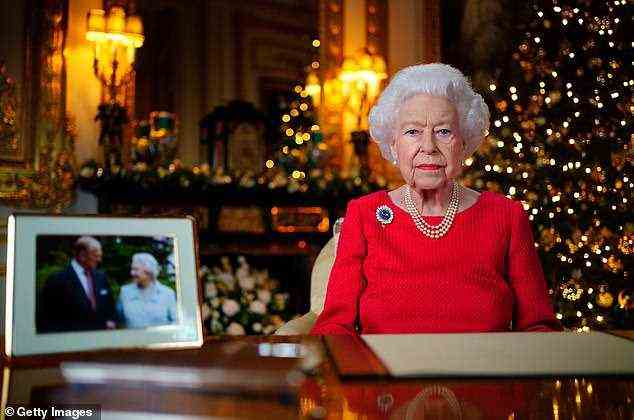 Die Königin wird ihrem „geliebten“ Prinzen Philip in der morgigen Weihnachtsbotschaft eine bewegende Hommage zollen, der neben einem gerahmten Bild des königlichen Paares (im Bild) saß.  Auf ihrer Jacke befindet sich die saphirfarbene Chrysantheme-Brosche, die sie im November letzten Jahres anlässlich ihres 73. Hochzeitstages mit Philip auf einem Foto trug