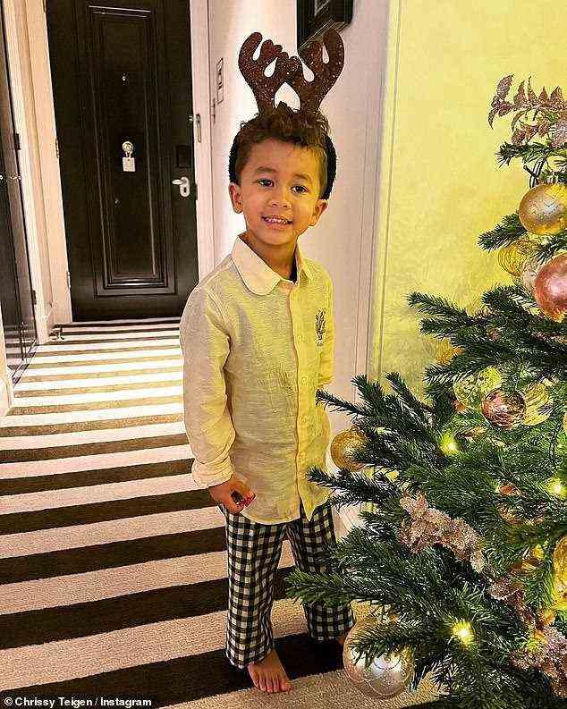 Now inside the home: Here the boy is seen with antlers on next to a Christmas tree