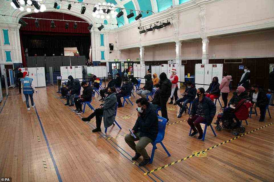 People wait in turn to receive a 'Jingle Jab' Covid vaccination booster injection at Redbridge Town Hall, in Ilford, Essex, today
