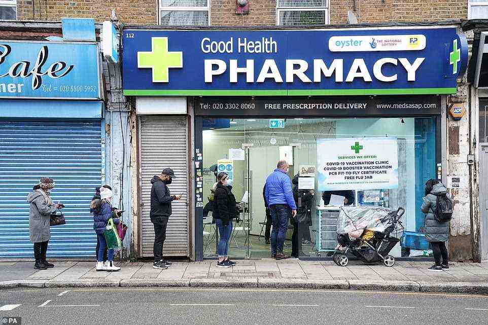 People wait in line to receive a 'Jingle Jab' Covid vaccination booster injection at the Good Health Pharmacy, north London