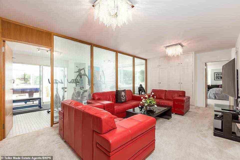 Einer der Loungebereiche im Erdgeschoss mit roten Ledersofas und einem riesigen Fernseher für die ganze Familie, der in den Fitnessraum führt