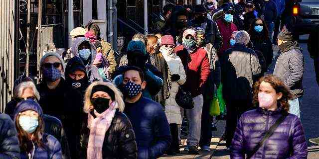 Die Einwohner der Stadt warten in einer Schlange, die sich um den Block erstreckt, um am Montag, den 20. Dezember 2021, in Philadelphia kostenlose COVID-19-Schnelltestkits zu Hause zu erhalten. (AP Photo/Matt Rourke)