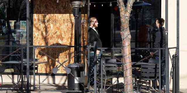 28. Dezember: Arbeiter beraten sich in der Nähe einer Sperrholzplatte, die ein Fenster einer Pizzeria in Lakewood, Colorado, bedeckt, in der Nähe einer der Szenen einer Amoklaufbahn, bei der fünf Menschen ums Leben kamen – darunter der mutmaßliche Schütze am Montagabend – und drei mehr Menschen verletzt.  (AP-Foto/David Zalubowski)