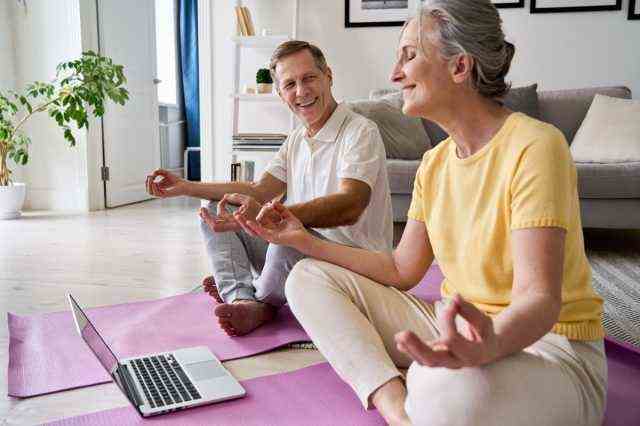 älteres Paar macht Yoga vor einem Laptop