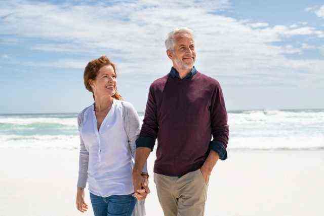 Älteres Paar zu Fuß am Strand.