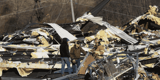 Rettungskräfte durchsuchen die Überreste der Mayfield Consumer Products Candle Factory, die von einem Tornado in Mayfield, Kentucky, zerstört wurde.  (Foto von John Amis / AFP) (Foto von JOHN AMIS / AFP über Getty Images)
