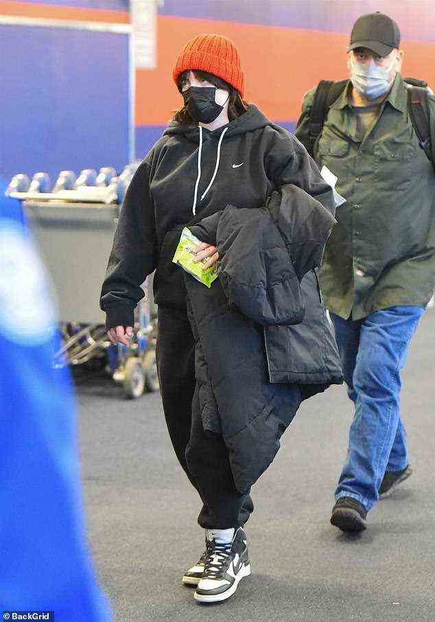 Obligatorisch: Die siebenmalige Grammy-Gewinnerin Billie Eilish trug eine schwarze Einweg-Gesichtsmaske, als sie am Montag einen Flug vom Flughafen JFK in New York nahm, wahrscheinlich zurück in ihre Heimatstadt Highland Park