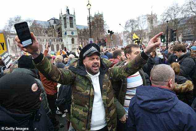Anti-Impfstoff-Demonstranten versammelten sich auf dem Londoner Parliament Square, darunter dieser Mann, der anscheinend einen Polizeihut trägt