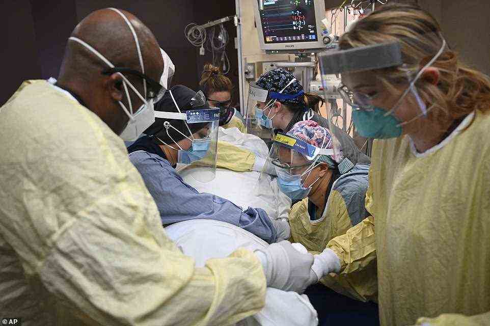 Hospitals in Michigan are being overwhelmed by COVID-19 patients as the state suffers what might be the early stages of a massive winter surge. Michigan leads the U.S. in hospitalizations and deaths from Covid per every 100,000 residents over the past seven days. Pictured: Health care workers treat a Covid patient in Robbinsdale, Michigan, on November 16