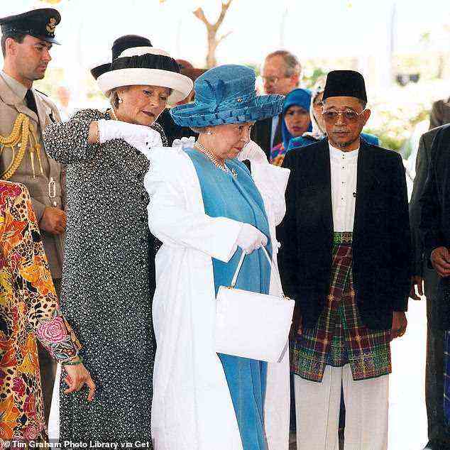 Lady Farnham hilft der Königin während einer Tour durch die Jame'asr Hassanal Bolkiah Moschee in Brunei . einen Mantel anzuziehen