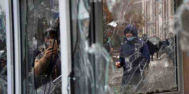Ein Mann macht ein Foto von Fenstern eines Polizeikiosks, die von Demonstranten während einer Protestaktion in Almaty, Kasachstan, am Mittwoch, 5. Januar 2022, beschädigt wurden. (AP Photo/Vladimir Tretyakov)