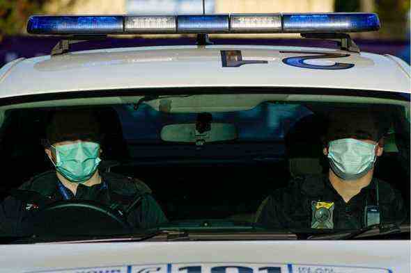 Polizisten tragen Gesichtsmasken, wenn sie im Auto patrouillieren