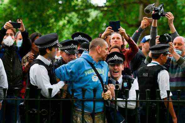 Ein Mann wird von der Polizei festgenommen als Medien mit Kameras und Smartphones umgeben