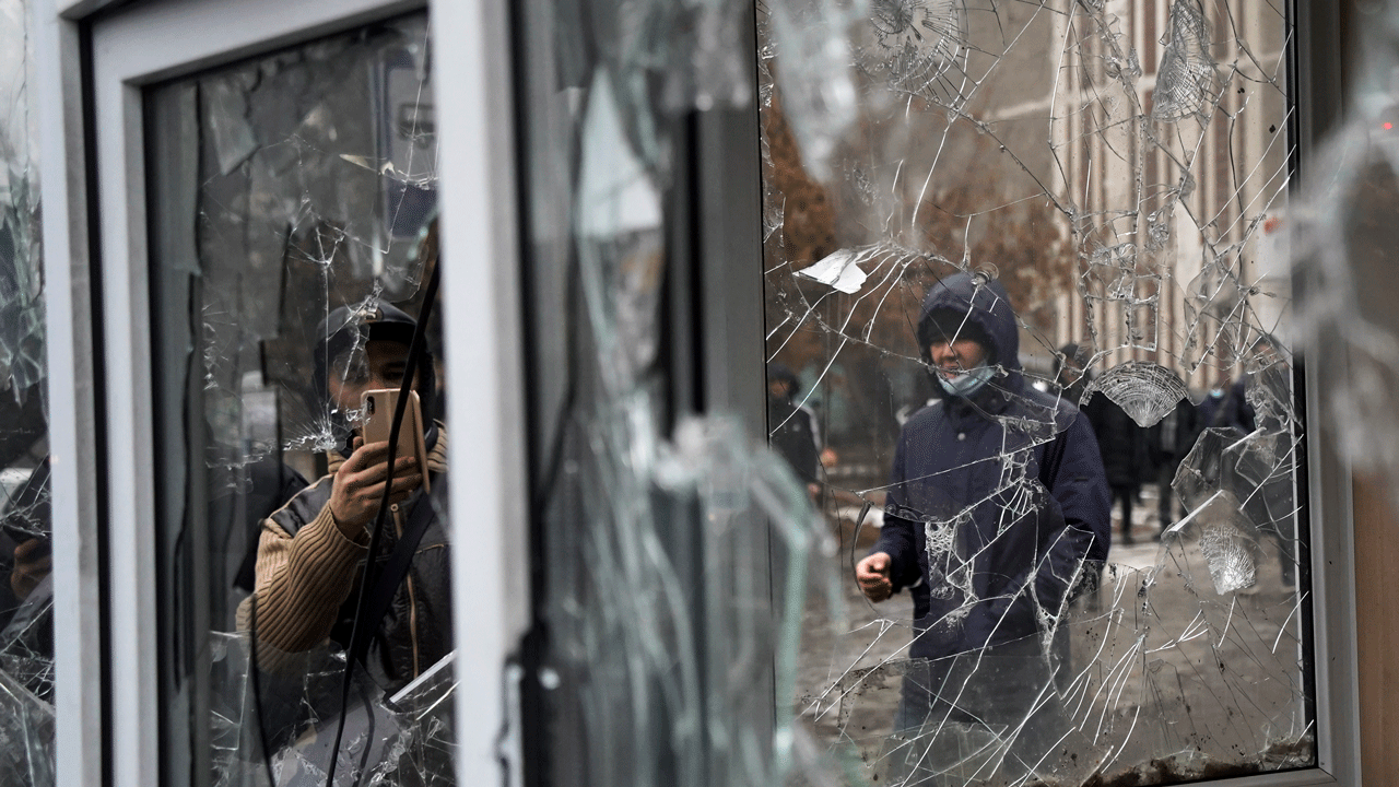 Ein Mann macht ein Foto von Fenstern eines Polizeikiosks, die von Demonstranten während einer Protestaktion in Almaty, Kasachstan, am Mittwoch, 5. Januar 2022, beschädigt wurden.