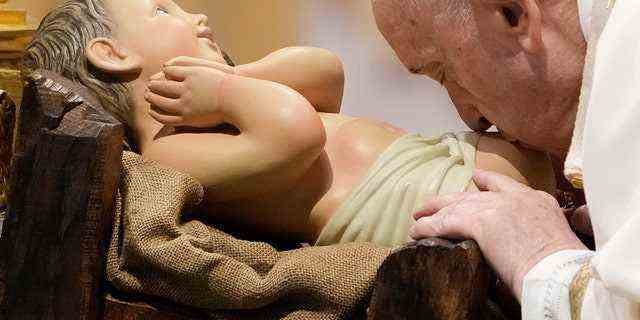 Papst Franziskus küsst eine Statue des Jesuskindes, während er am Donnerstag, den 6. Januar 2022, eine Epiphanie-Messe im Petersdom im Vatikan feiert. 