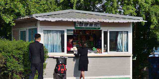 Pjöngjang, Nordkorea - 5. Mai 2019: Straßenszene.  Frau kauft Lebensmittel in einem kleinen Laden auf der Straße.