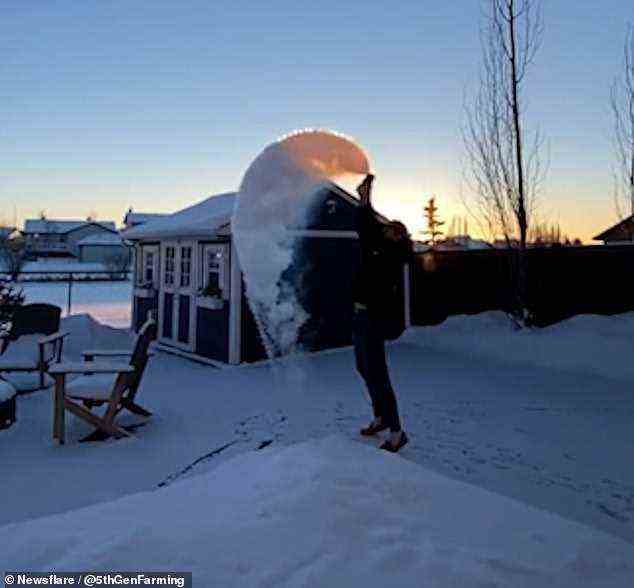 Der Bewohner wirft das kochende Wasser in kreisenden Bewegungen über seinen Kopf, bevor es am 27. Dezember in Alberta, Kanada, zu Eis wird