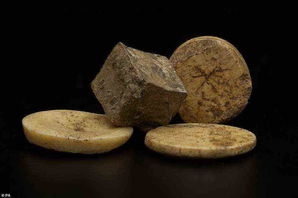 Another image of the Roman lead die surrounded by bone gaming pieces uncovered during the HS2 archaeology excavation