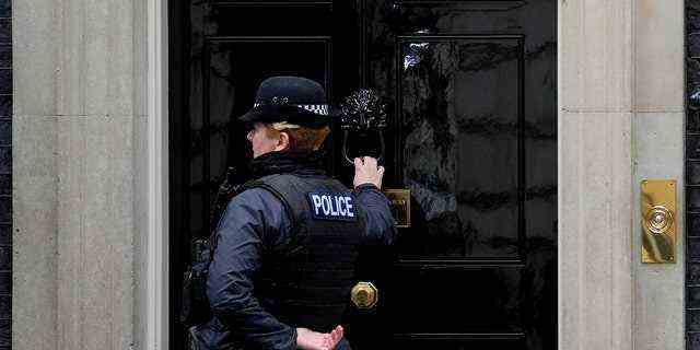 Ein Polizist klopft an die Tür der Downing Street 10 in London, Dienstag, 11. Januar 2022. Die Polizei steht in Kontakt mit dem Kabinettsbüro wegen Behauptungen, der Berater des Premierministers habe organisiert "Bring deinen eigenen Schnaps" Downing Street Party im Mai 2020 während der ersten Virussperre.