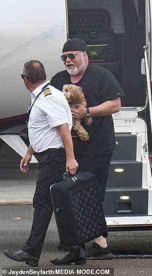 Hündchen: Er trug seinen entzückenden Hund die Treppe des Jets hinunter, während der Pilot ihm mit seinem Handgepäck von Louis Vuitton half