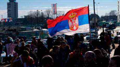 Fans schwenken eine serbische Flagge, als der serbische Tennisspieler Novak Djokovic am Montag, den 17. Januar, am Flughafen Nikola Tesla in Belgrad, Serbien, ankommt. 