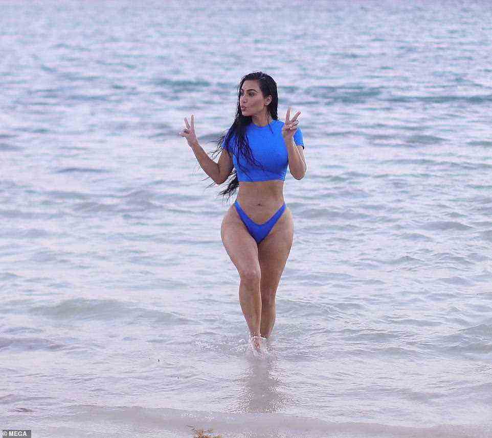 Playful: Kim also posed for a fun snap while giving double peace signs in the water
