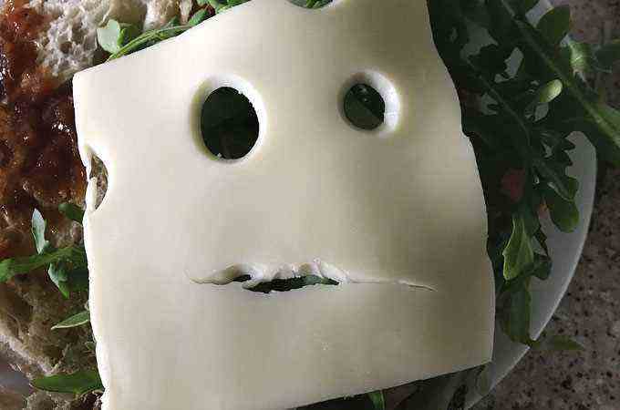 Bild einer Käsescheibe mit Löchern, die wie ein Gesicht aussehen