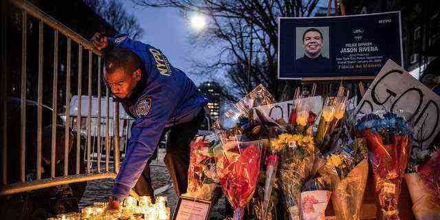 DATEI – Ein Beamter der New Yorker Polizeibehörde zündet eine Kerze an einem provisorischen Denkmal außerhalb des 32 24., 2022. (AP Photo/Yuki Iwamura, Akte)