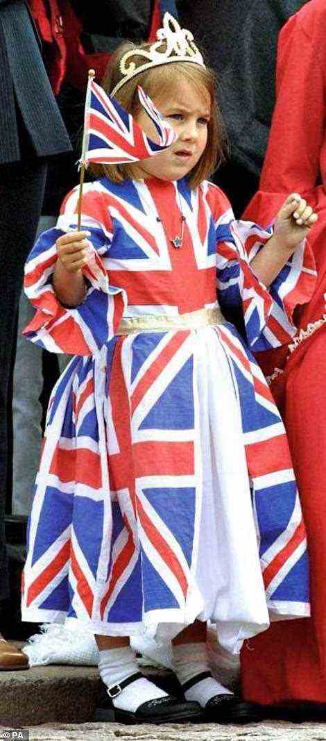 A girl wearing a Union Jack flag dress as she watches the procession outside Buckingham Palace during the Golden Jubilee celebrations in London