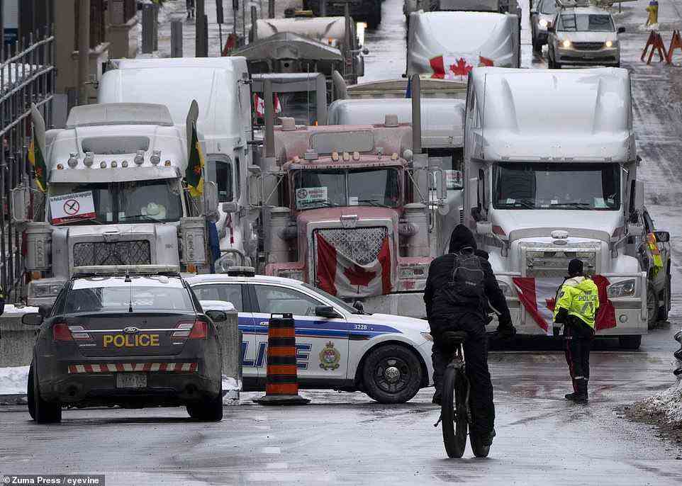 A cyclist rides towards a police barricade where trucks are lined up near Parliament hill on Wednesday