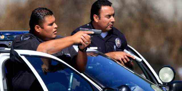 LAPD-Beamte ziehen ihre Waffen, während sie an der Ecke Gage und Grand in Süd-Los Angeles einen Verkehrsstopp machen.