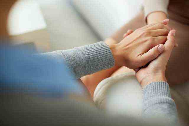 Nahaufnahme der Hände der Psychiaterin, die die Handfläche ihrer Patientin zusammenhält