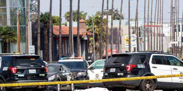 Ein LAPD-Polizist steht an der Ecke Fairfax Avenue und Sunset Boulevard, wo am 24. April 2021 in Los Angeles eine mit einem weißen Laken bedeckte Leiche auf dem Bürgersteig liegt. (Foto von VALERIE MACON/AFP über Getty Images)