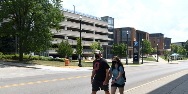 Studenten, die Schutzmasken tragen, gehen am Dienstag, den 25. August 2020, während des ersten Unterrichts der Ohio State University in Columbus, Ohio, USA, über den Campus.
