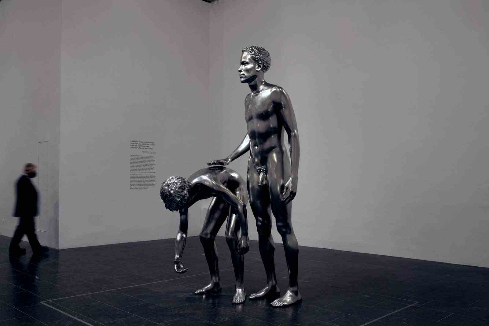 Silberne Skulptur eines erwachsenen flüchtigen Sklaven, der neben einem entlaufenen Jungen steht, der sich bückt, um etwas vom Boden aufzuheben.